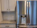 Remodeled kitchen with stainless steel fridge.