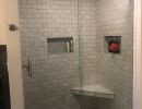 Remodeled bathroom with glass door shower and gray tile finish.